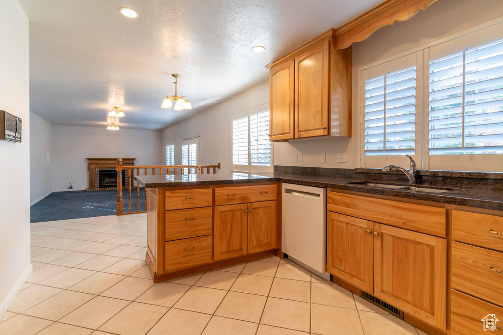 Kitchen with pendant lighting, dishwasher, a fireplace, and a healthy amount of sunlight