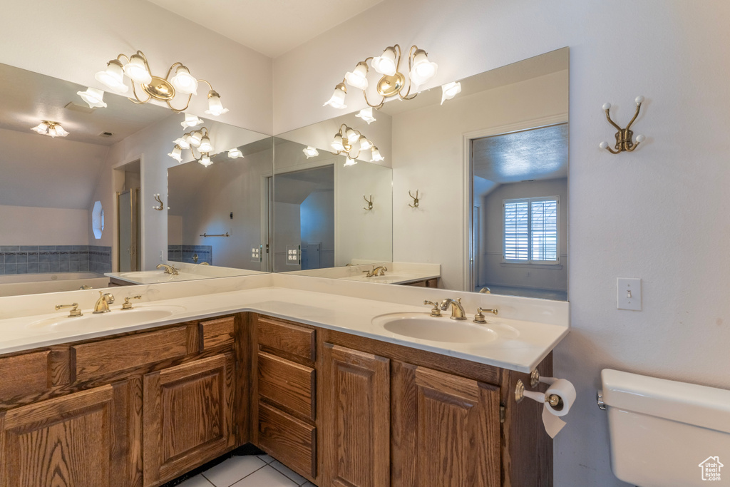 Bathroom with a washtub, vanity, tile patterned flooring, and toilet