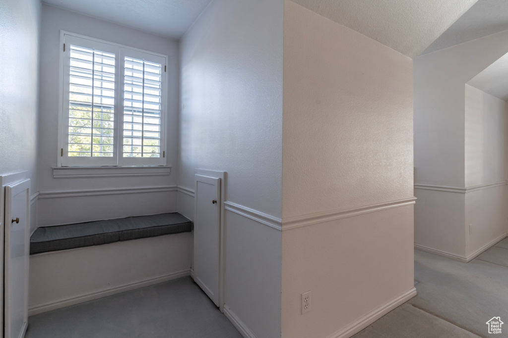 Hallway with light colored carpet and a textured ceiling