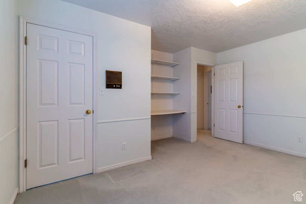 Unfurnished bedroom with light carpet and a textured ceiling