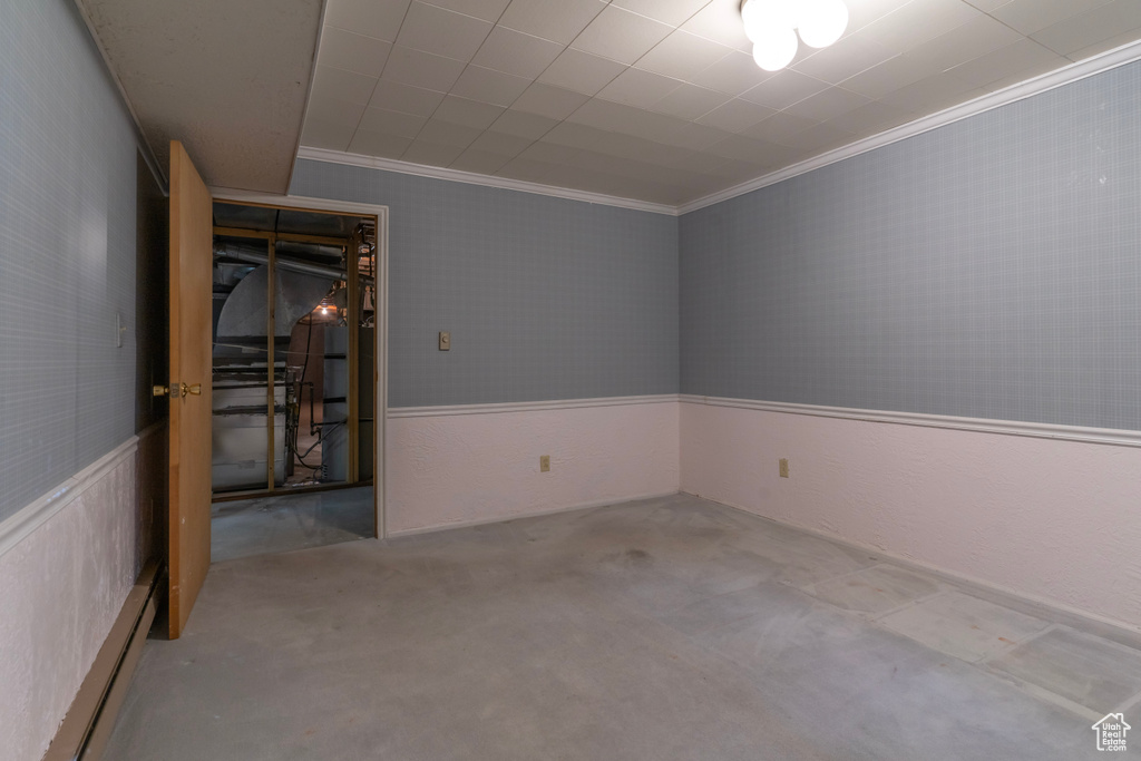 Spare room featuring crown molding, a baseboard radiator, and concrete flooring