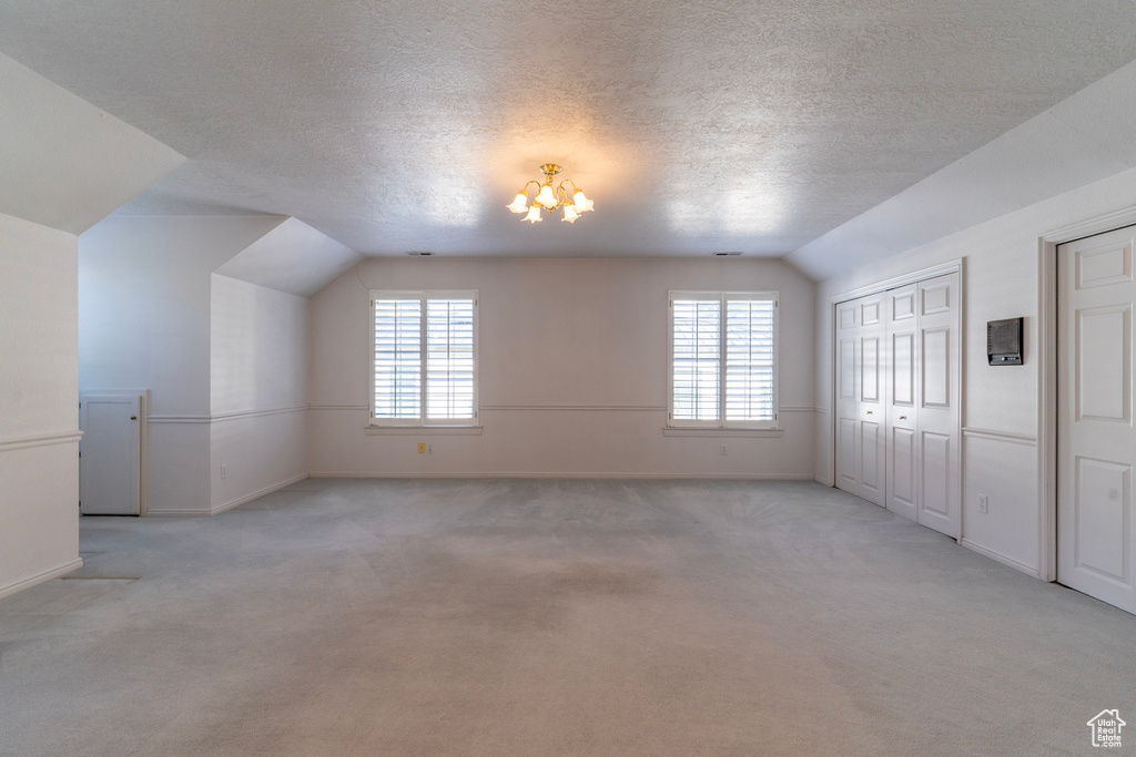 Interior space featuring lofted ceiling, light carpet, a chandelier, and a textured ceiling