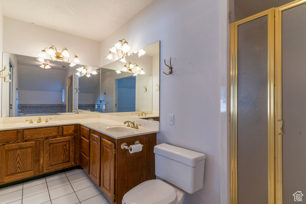 Bathroom featuring vanity, tile patterned flooring, toilet, and a shower with door