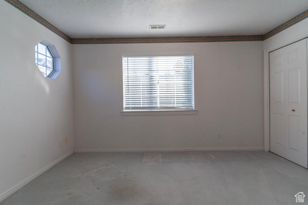 Carpeted spare room with a textured ceiling and a healthy amount of sunlight