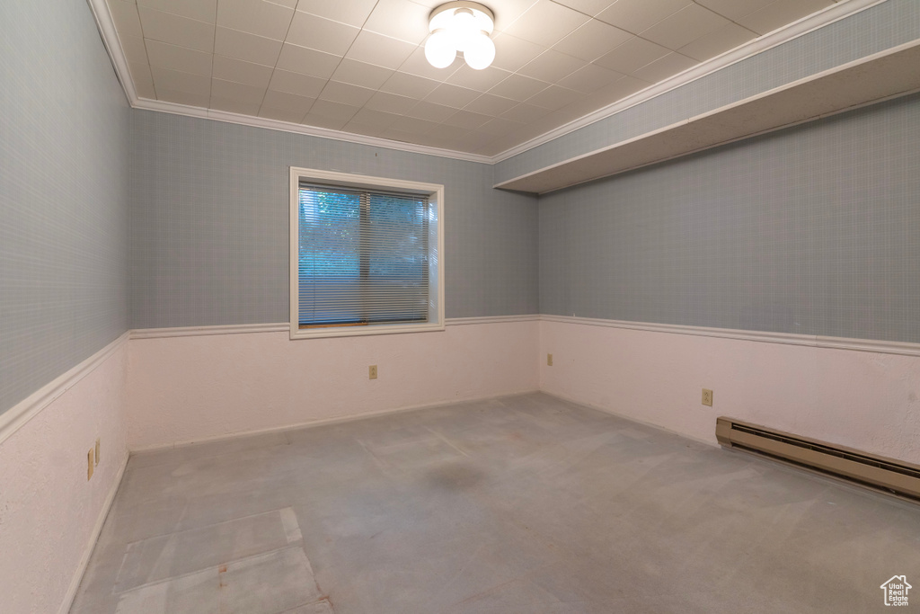 Empty room with crown molding, baseboard heating, and light carpet