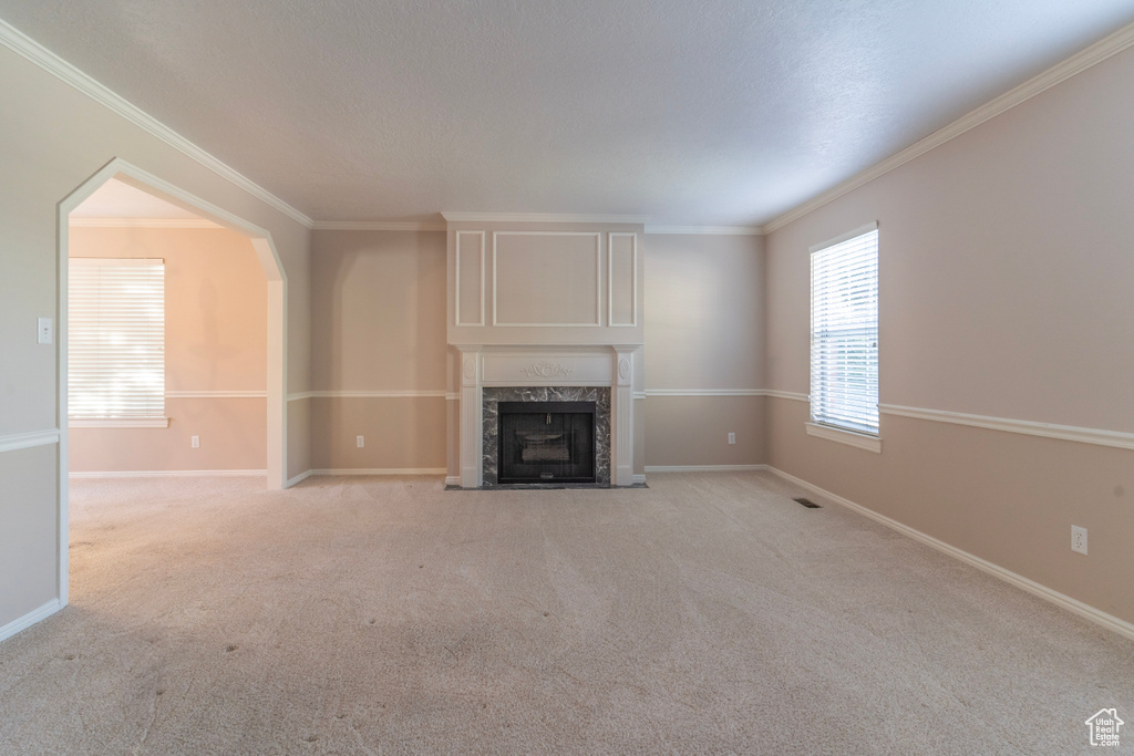 Unfurnished living room with ornamental molding, a fireplace, and light colored carpet