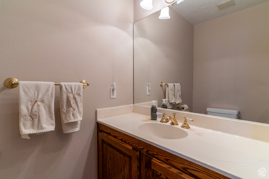 Bathroom featuring vanity, toilet, and a textured ceiling