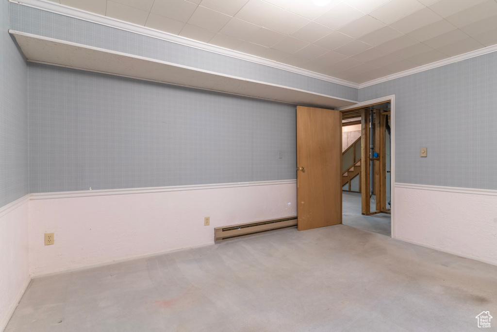 Carpeted empty room featuring ornamental molding and baseboard heating