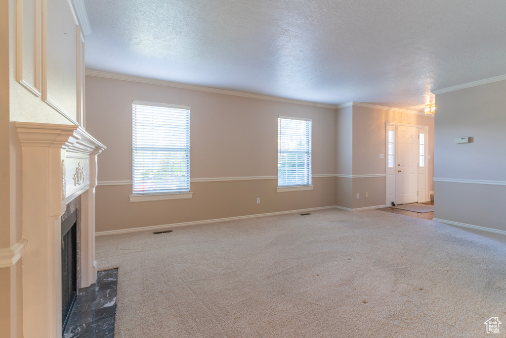 Unfurnished living room featuring a textured ceiling, crown molding, and carpet flooring