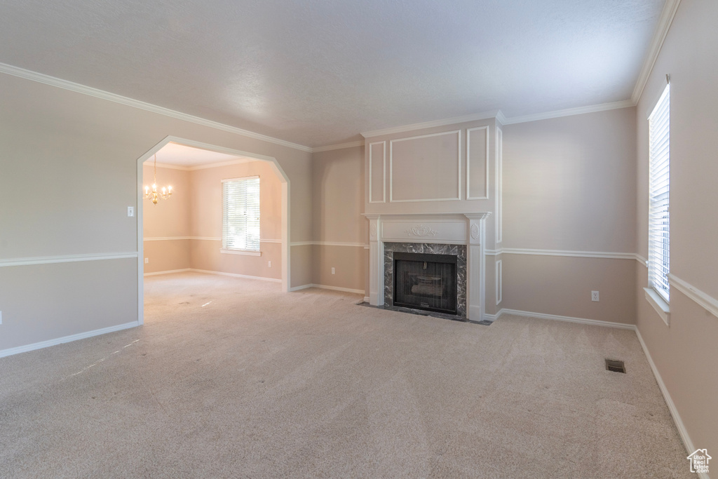 Unfurnished living room featuring light carpet, crown molding, and a fireplace