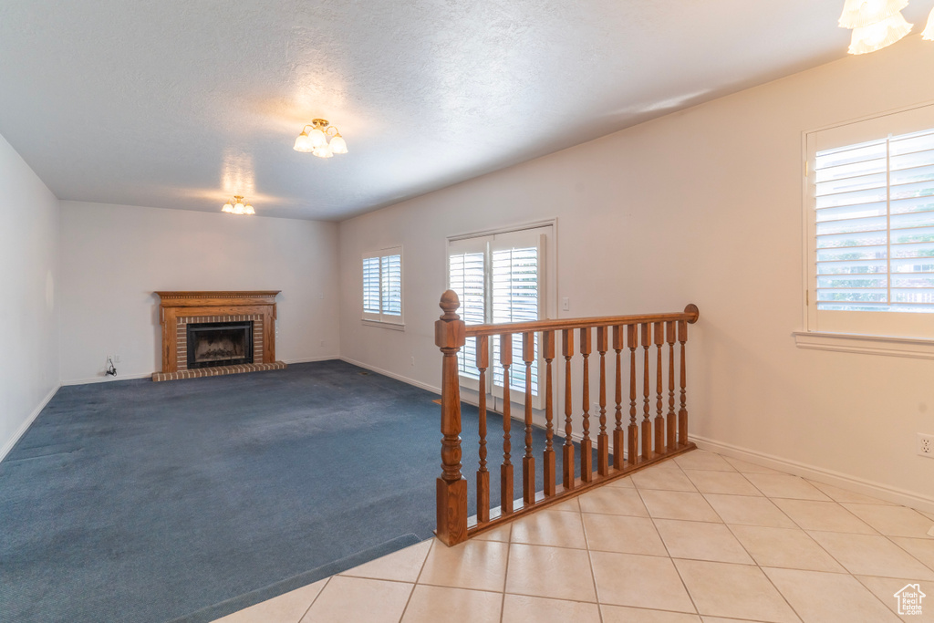 Living room featuring a fireplace, light carpet, a wealth of natural light, and a textured ceiling