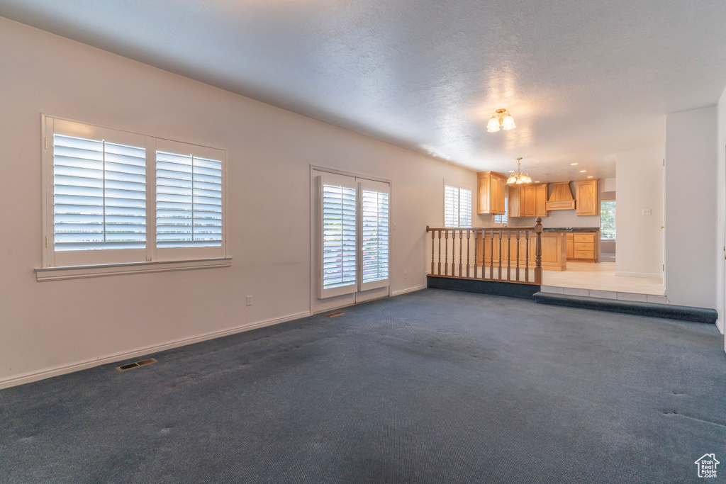 Spare room with plenty of natural light, dark colored carpet, and a textured ceiling