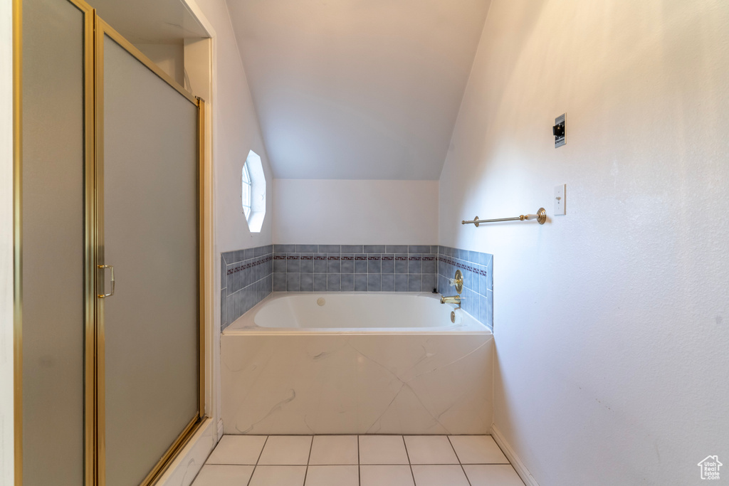 Bathroom with shower with separate bathtub, vaulted ceiling, and tile patterned floors