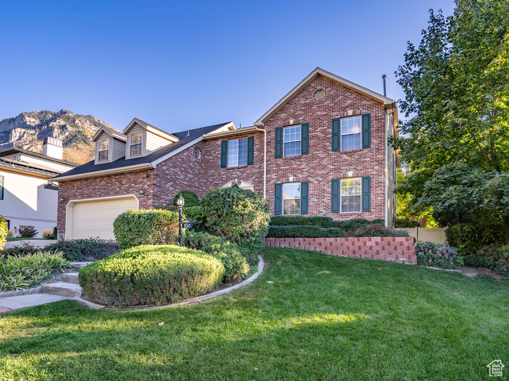 View of front of house featuring a front lawn, a mountain view, and a garage