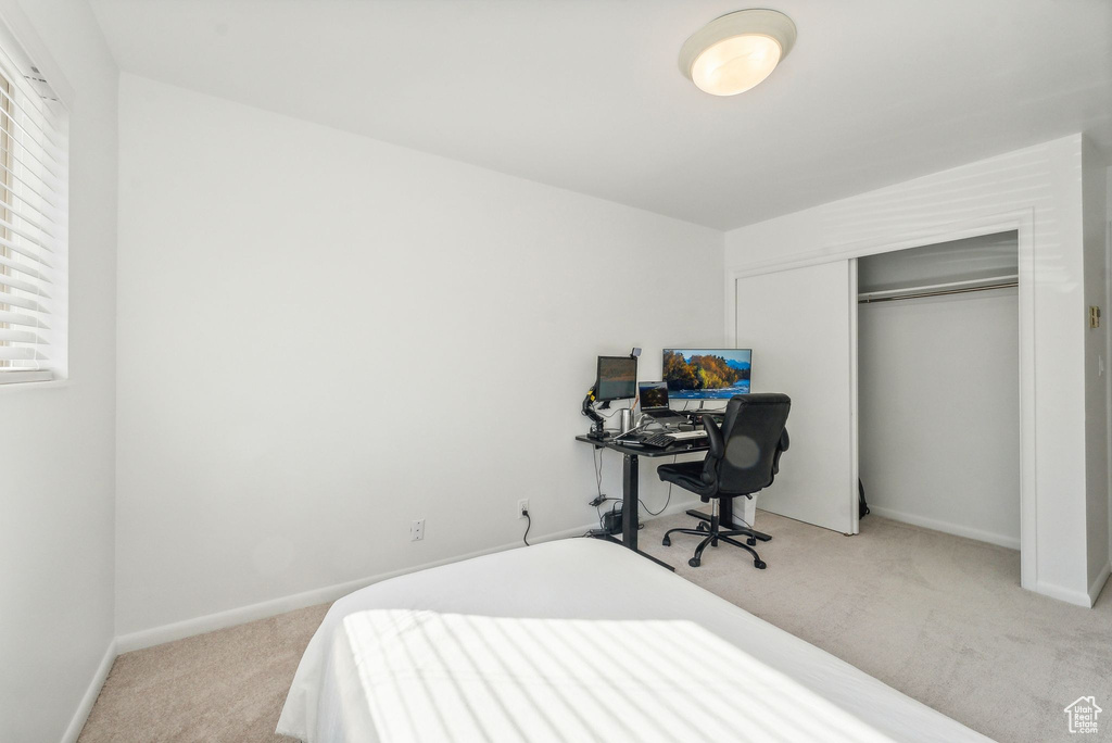 Bedroom with light colored carpet and a closet