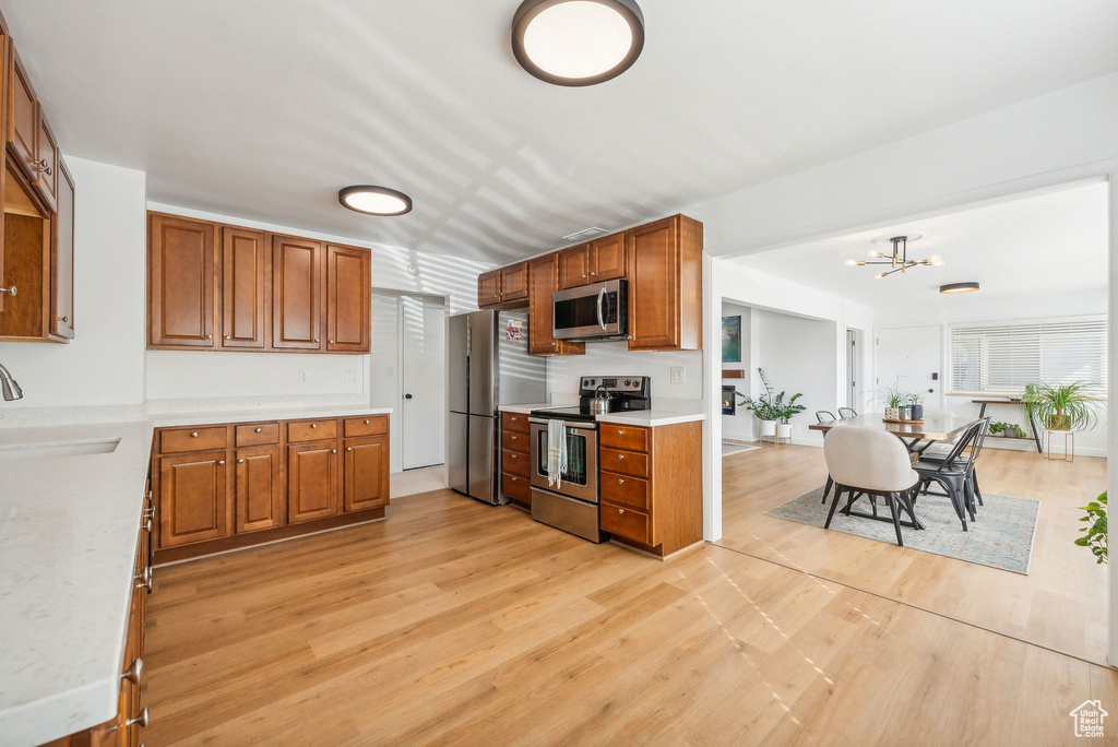 Kitchen featuring light hardwood / wood-style flooring, appliances with stainless steel finishes, sink, and a chandelier