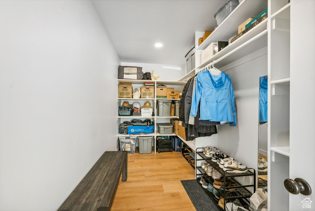 Walk in closet with hardwood / wood-style flooring