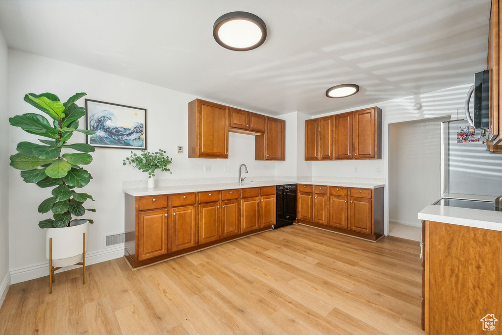 Kitchen with light hardwood / wood-style floors, sink, and black dishwasher