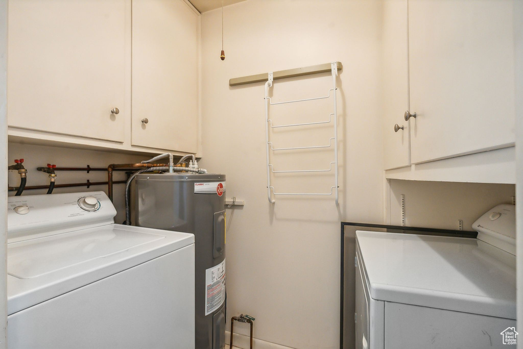 Laundry area featuring washer and dryer, cabinets, and water heater