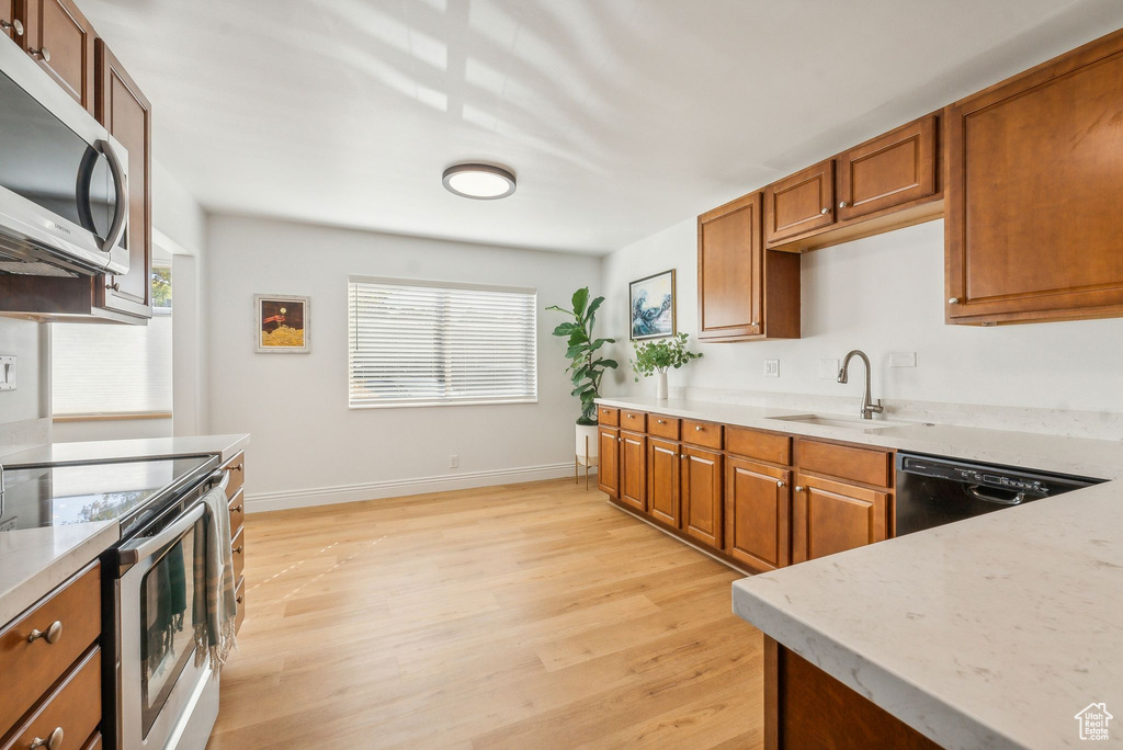 Kitchen with appliances with stainless steel finishes, light hardwood / wood-style flooring, sink, and a wealth of natural light