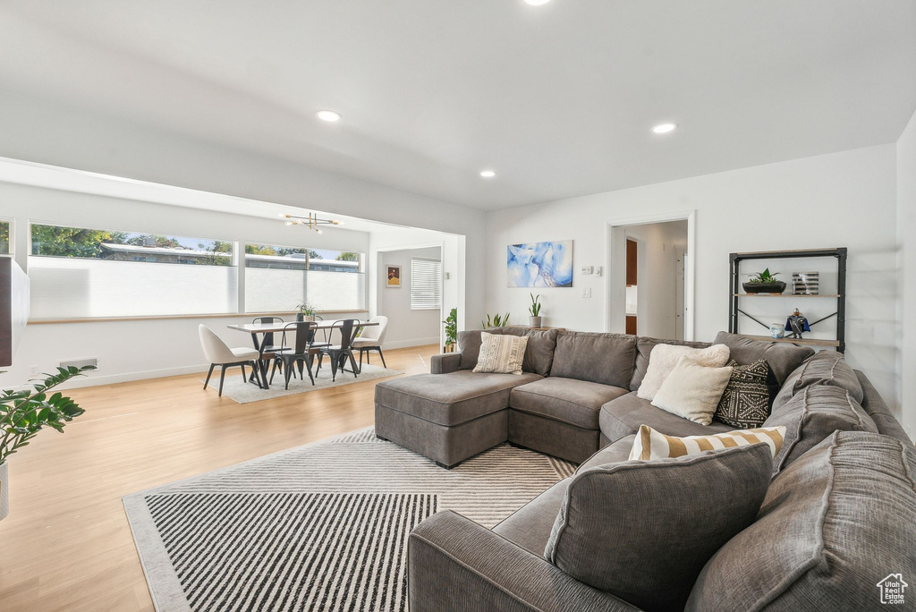 Living room with light hardwood / wood-style floors and a notable chandelier