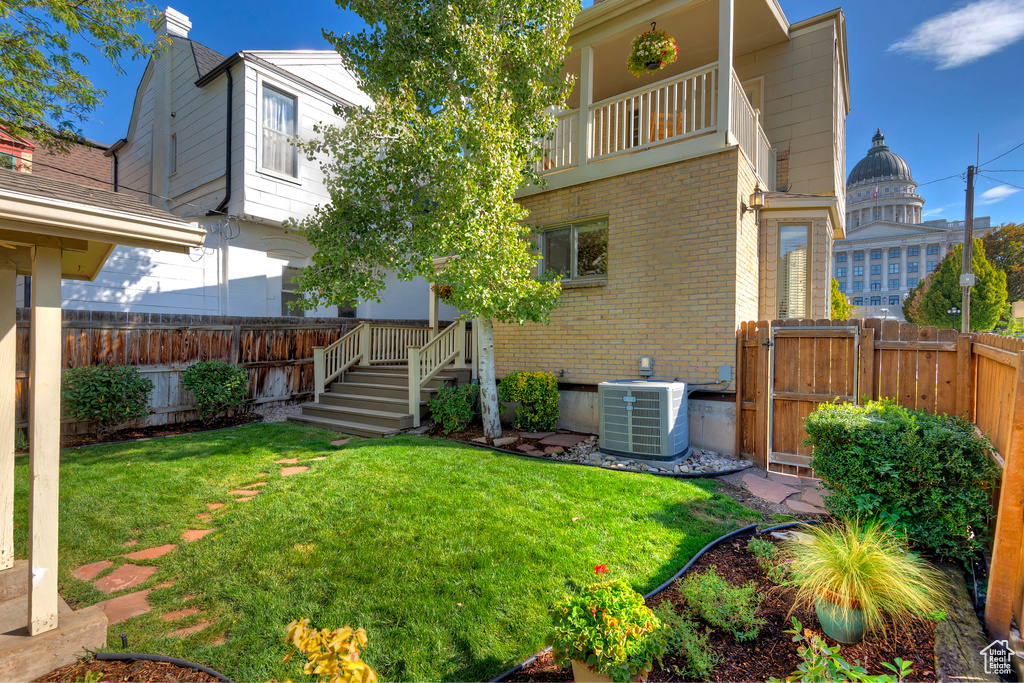 View of yard with central AC and a balcony