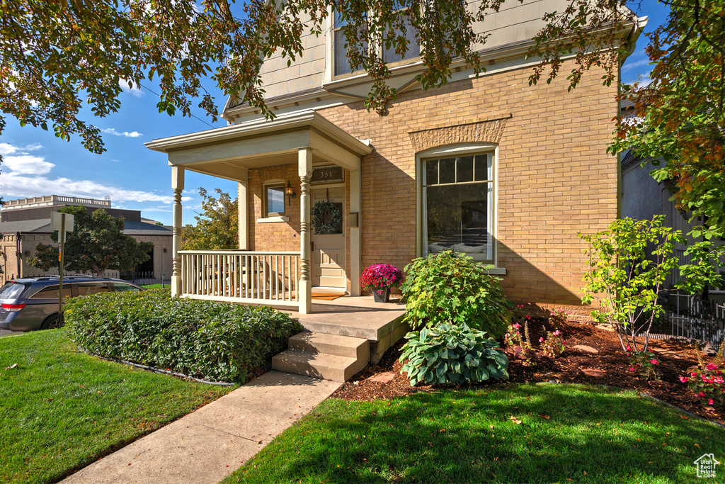 View of exterior entry featuring a porch and a yard