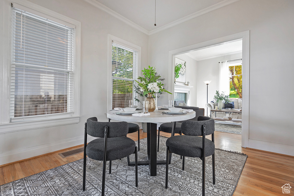 Dining area featuring a wealth of natural light, ornamental molding, and hardwood / wood-style flooring