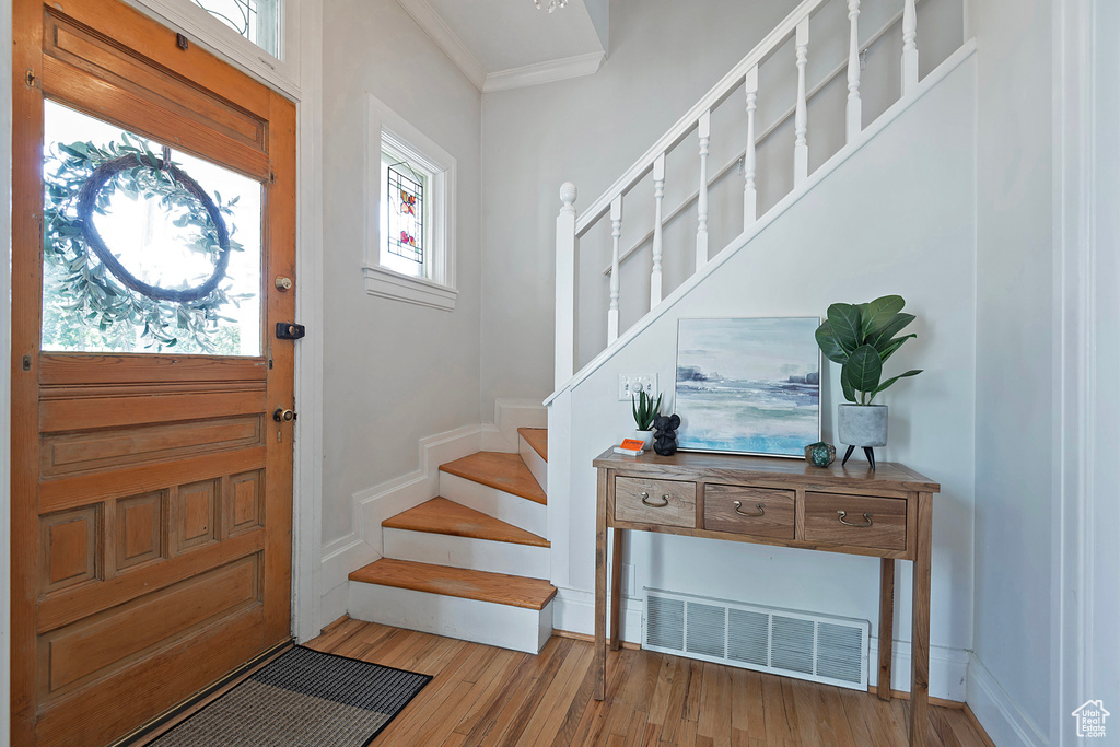 Foyer featuring light hardwood / wood-style flooring, crown molding, and a wealth of natural light