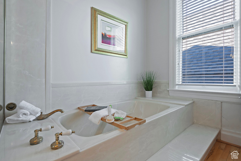 Bathroom with a wealth of natural light, a bathtub, and wood-type flooring