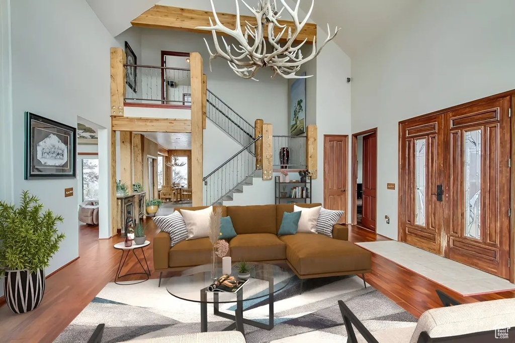 Living room with high vaulted ceiling, hardwood / wood-style flooring, and an inviting chandelier