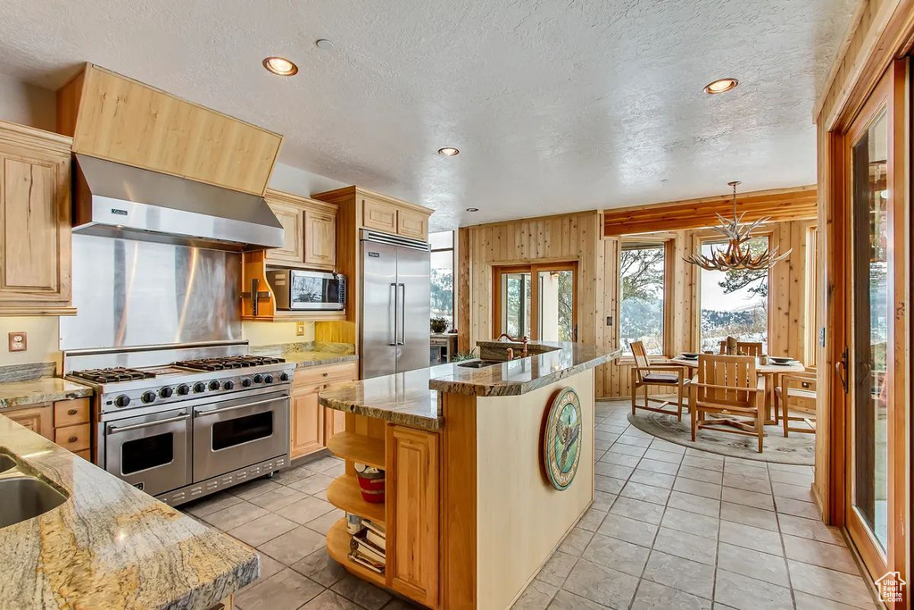 Kitchen with built in appliances, a textured ceiling, and light brown cabinets