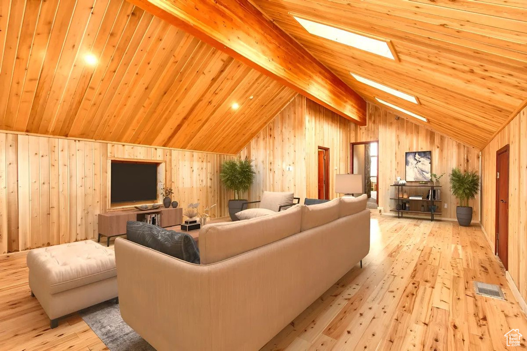 Living room with wood walls, vaulted ceiling with skylight, light hardwood / wood-style flooring, and wooden ceiling