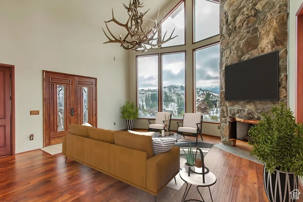 Living room with a stone fireplace, hardwood / wood-style flooring, and a towering ceiling