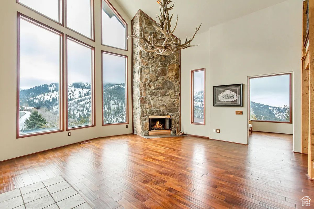 Unfurnished living room with a high ceiling, a mountain view, a stone fireplace, and light wood-type flooring