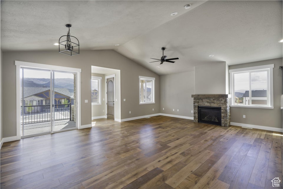 Unfurnished living room with dark wood-type flooring, a mountain view, lofted ceiling, and plenty of natural light