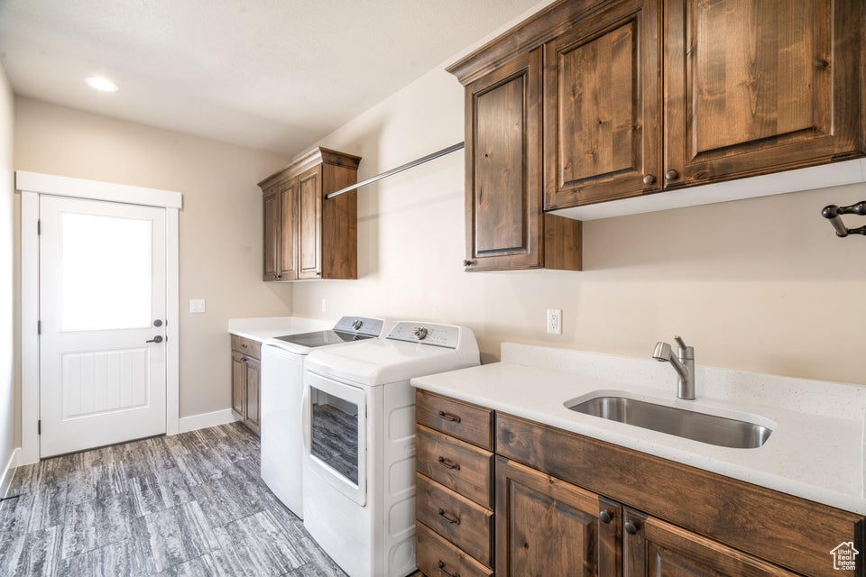 Clothes washing area featuring cabinets, washer and dryer, sink, and hardwood / wood-style floors