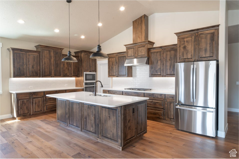 Kitchen featuring sink, hanging light fixtures, stainless steel appliances, and hardwood / wood-style flooring