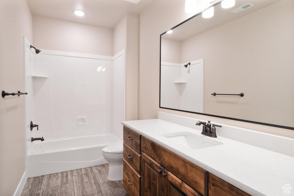Full bathroom with bathtub / shower combination, vanity, hardwood / wood-style floors, and toilet