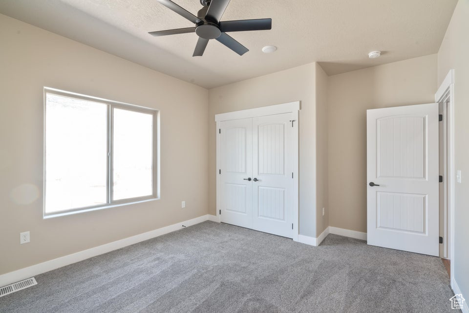 Unfurnished bedroom with light colored carpet, a closet, and ceiling fan
