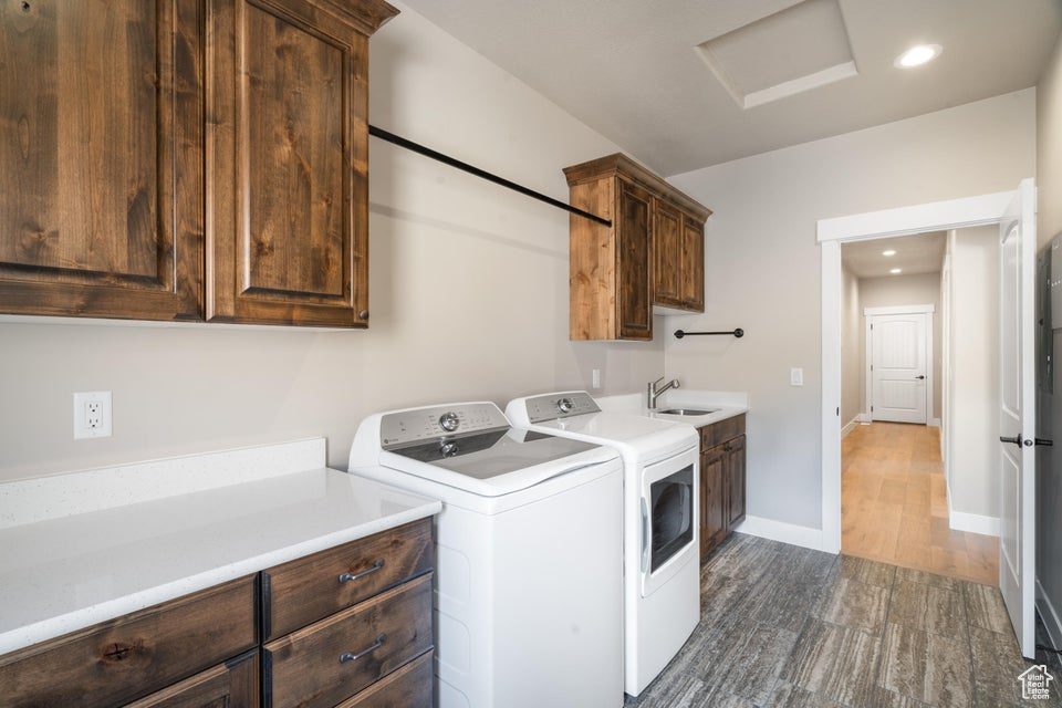 Washroom with sink, dark hardwood / wood-style floors, separate washer and dryer, and cabinets