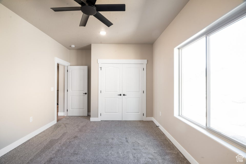 Unfurnished bedroom with ceiling fan and light carpet