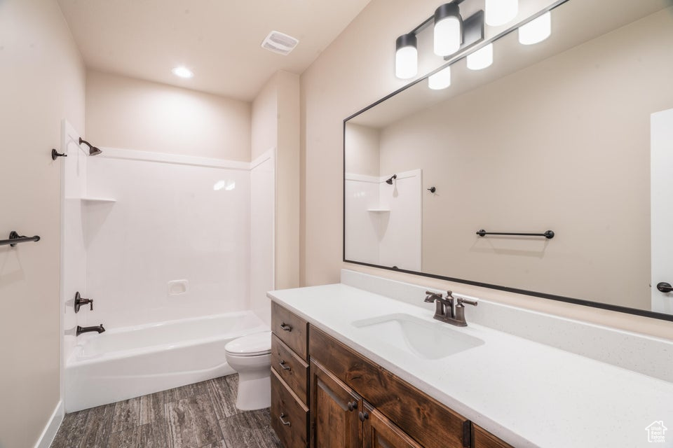 Full bathroom with toilet, hardwood / wood-style flooring, vanity, and  shower combination