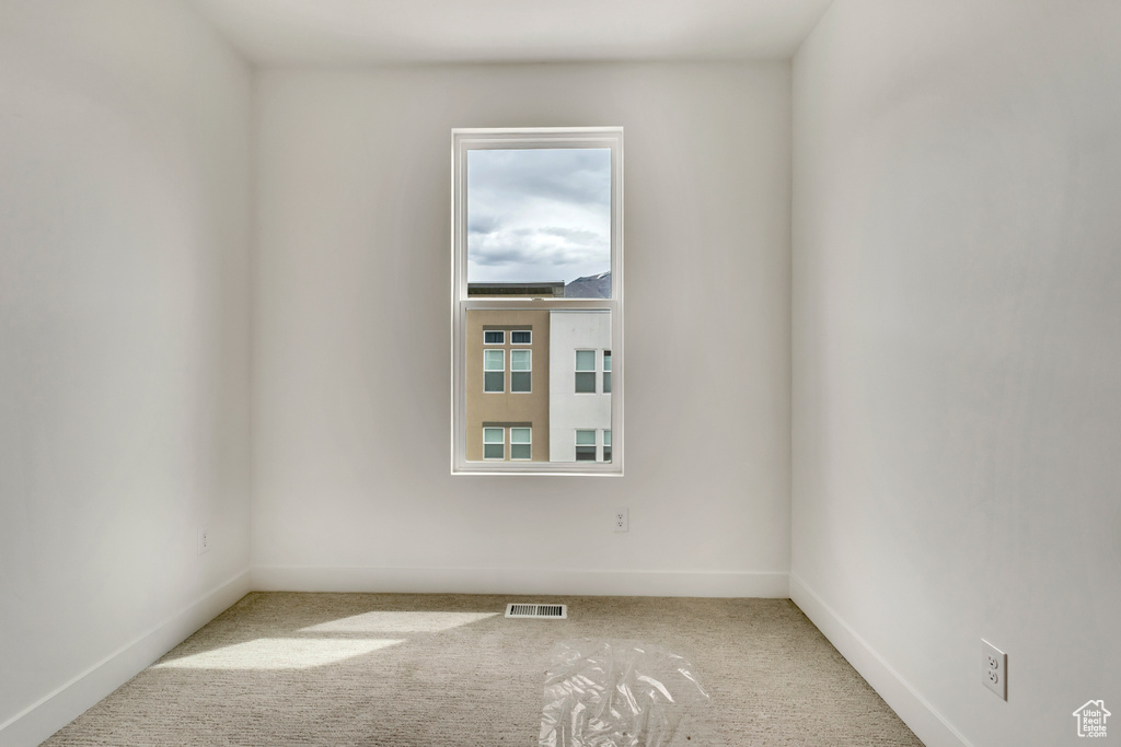 Carpeted spare room with visible vents and baseboards
