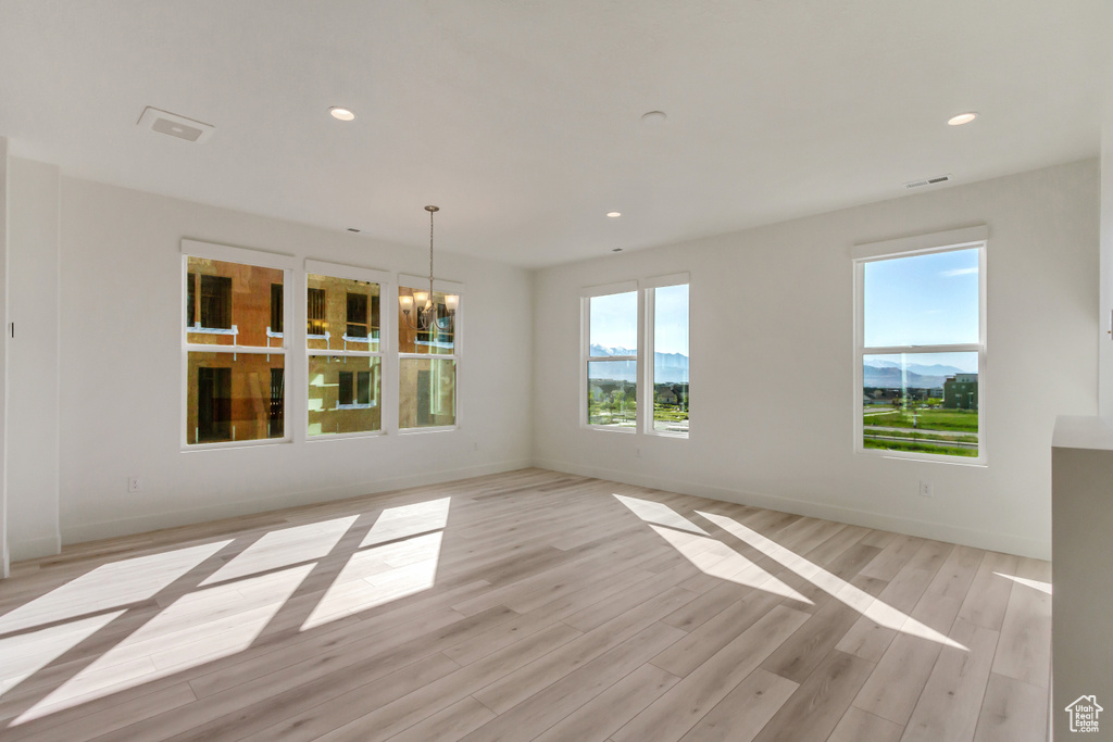 Unfurnished room with light hardwood / wood-style flooring and a notable chandelier