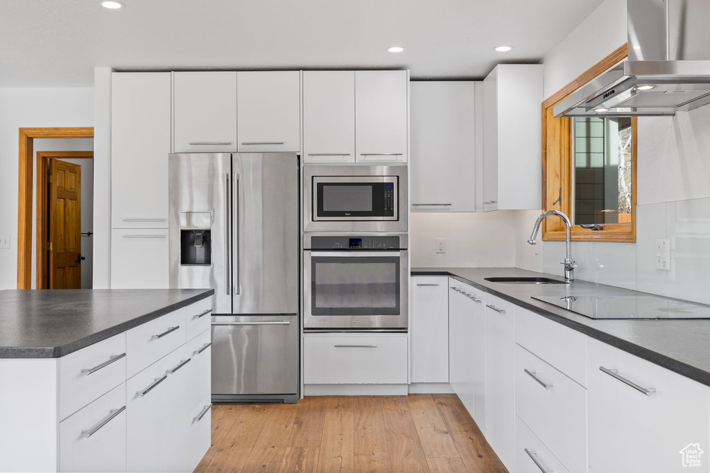 Kitchen with white cabinets, stainless steel appliances, wall chimney exhaust hood, and sink