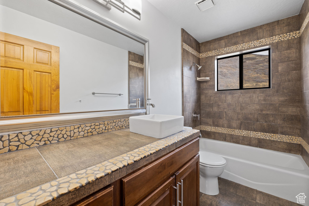 Full bathroom with hardwood / wood-style floors, vanity, toilet, and tiled shower / bath