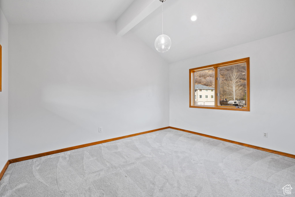 Empty room with lofted ceiling with beams and carpet flooring