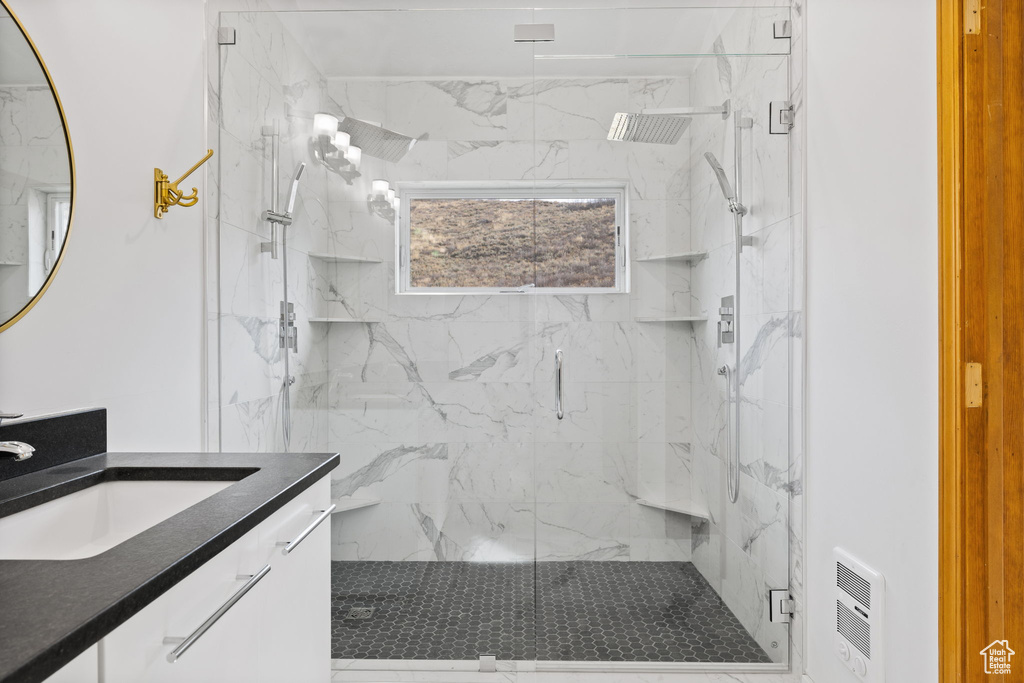 Bathroom with an enclosed shower, heating unit, and vanity