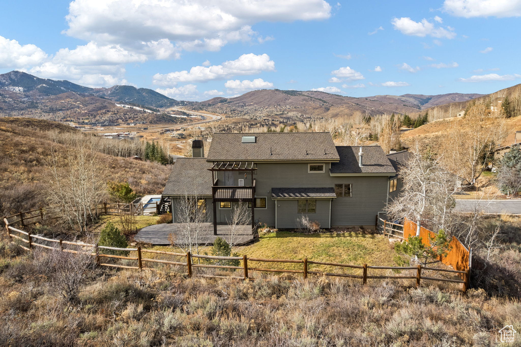 Rear view of property with a rural view, a lawn, and a mountain view